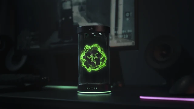 Razer Project AVA cylindrical desk device displaying a glowing green symbol in a dark desktop setup